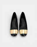 Black patent leather pumps with gold toe caps